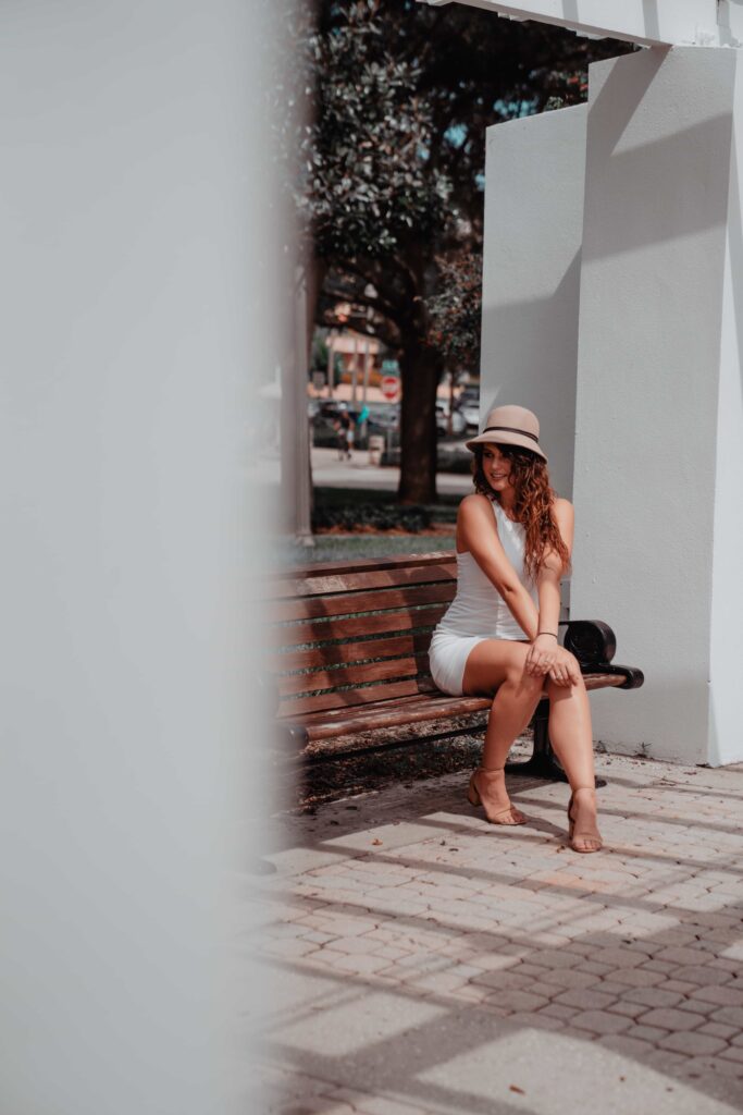 Aimee Albright in a white dress sitting on a bench at North Straub Park in downtown st petersburg